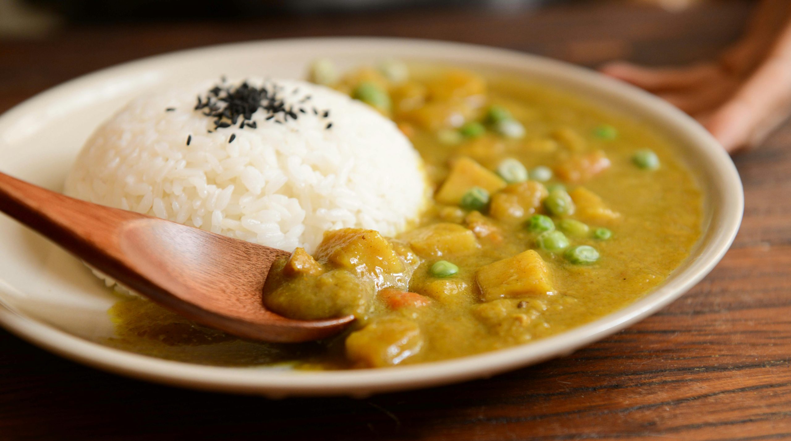 A delicious plate of creamy vegetable curry served with rice and a wooden spoon, perfect for a tasty meal.